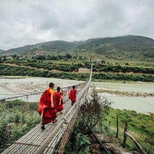 Monks walking over a bridge in Bhutan