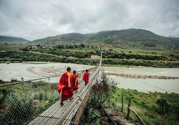 Monks walking over a bridge in Bhutan