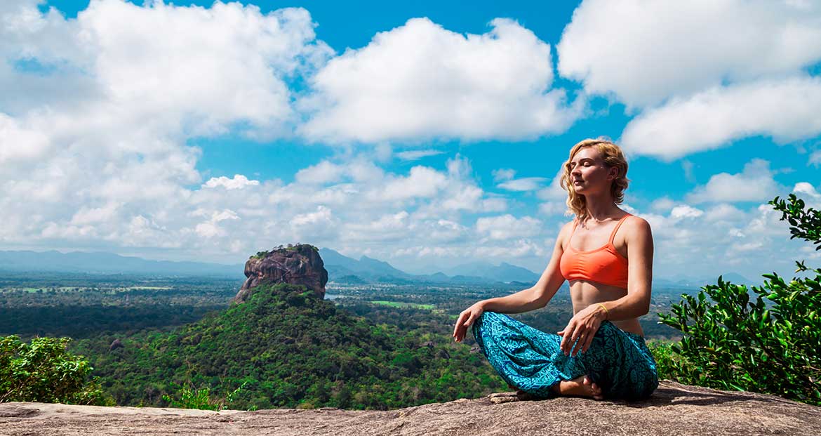 Young woman meditation on the mountain Pidurangala Rock, Sri Lanka