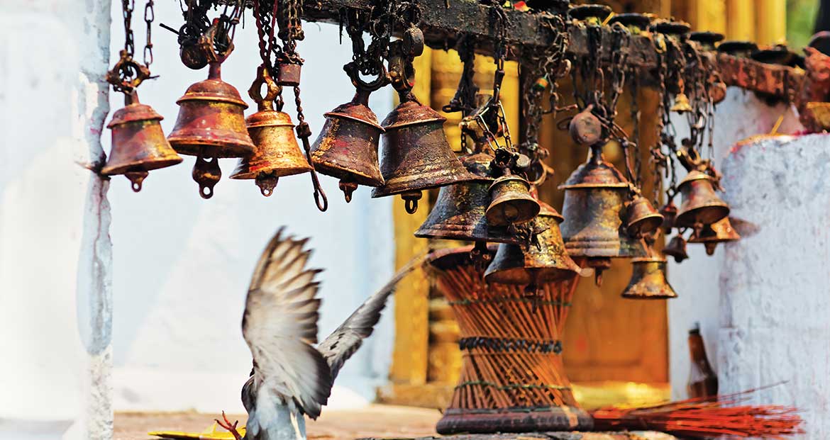 Many metal sacrificial bells hanging on chain and landing dove, Pokhara